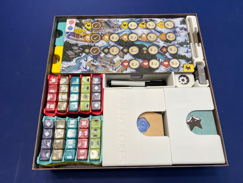 May include: A white organizer insert for the board game "The Crew: The Quest for Planet Nine". The insert has compartments for the game's cards, dice, and tokens. The insert is labeled "Parent Foxes".