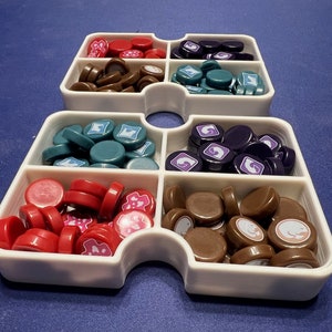 May include: White plastic tray with six compartments, each filled with different colored game pieces. The compartments contain red, brown, teal, purple, brown, and white game pieces.