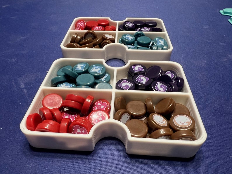 May include: White plastic tray with six compartments, each filled with different colored game pieces. The compartments contain red, brown, teal, purple, brown, and white game pieces.