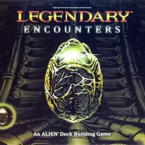 Op de afbeelding: Een speldoos voor "Legendary Encounters: An Alien Deck Building Game". De doos heeft een gouden alien-ei met een gloeiend groene binnenkant op een donkere achtergrond met een patroon van metalen roosters. De tekst "Legendary Encounters" staat in grote, vetgedrukte letters boven het ei.