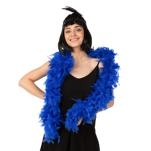 Pode incluir: Uma mulher vestindo um vestido preto e um boa de penas azul. Ela está sorrindo e olhando para a câmera.