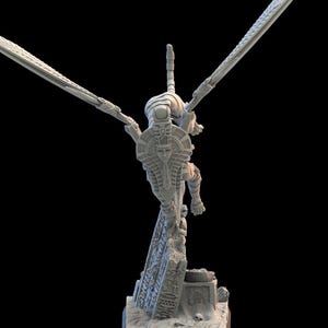 Pode incluir: Uma escultura cinza impressa em 3D de uma figura com asas abertas, assemelhando-se a um faraó egípcio. A figura está em pé sobre uma base de pedra com hieróglifos. As asas são longas e detalhadas, e a figura usa um cocar.