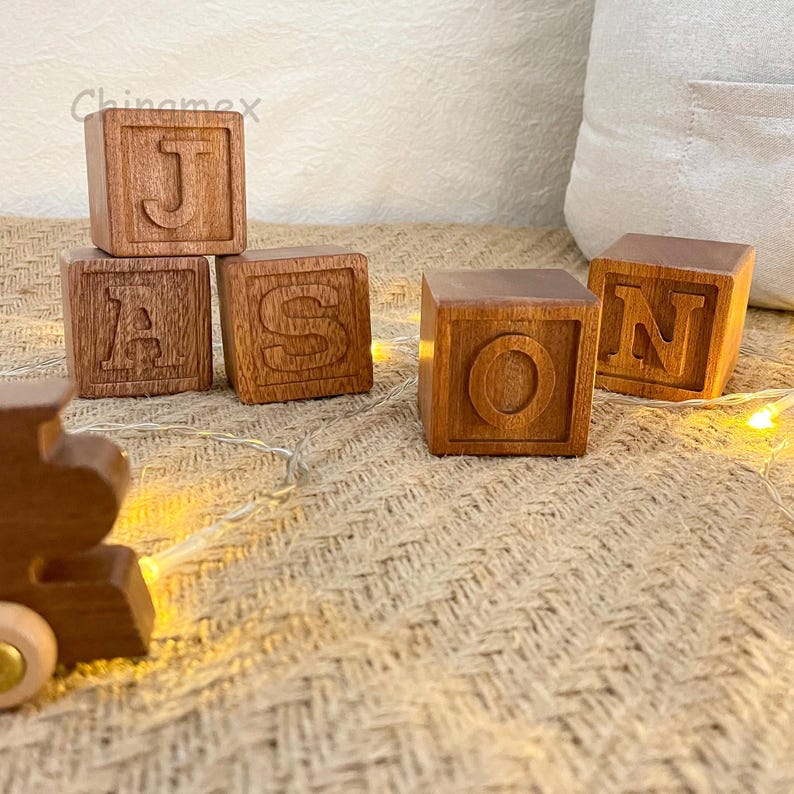 May include: Four wooden blocks spelling out the name "Jason" in all-caps. The blocks are a light brown colour and have a smooth, polished finish.