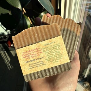 May include: Two bars of handmade soap with a brown and black marbled design. The soap is labeled with the ingredients: Saponified Oils (Coconut Oil, Olive Oil, Sustainable Palm Oil, Rice Bran Oil & Castor Oil), Guinness Extra Stout Beer, Oatmeal, Activated Charcoal, Coffee Grinds, Kaolin Clay, Skin Safe Colorant & Sodium Lactate. The soap is handcrafted locally in Manhattan, NY. Find us at Southside Tobacco & Vape 24520 US-52, #11. Chill PillBath Co. Etsy.com Cold Processed Soap made with sustainably harvested oils & lots of love.