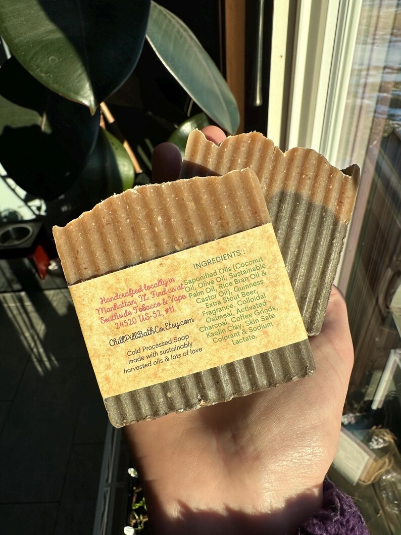 May include: Two bars of handmade soap with a brown and black marbled design. The soap is labeled with the ingredients: Saponified Oils (Coconut Oil, Olive Oil, Sustainable Palm Oil, Rice Bran Oil & Castor Oil), Guinness Extra Stout Beer, Oatmeal, Activated Charcoal, Coffee Grinds, Kaolin Clay, Skin Safe Colorant & Sodium Lactate. The soap is handcrafted locally in Manhattan, NY. Find us at Southside Tobacco & Vape 24520 US-52, #11. Chill PillBath Co. Etsy.com Cold Processed Soap made with sustainably harvested oils & lots of love.