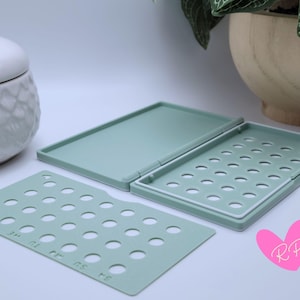 Mint green diamond-pattern pill case open with pack cover next to it – displays pill access holes and interior structure custom-fit for your birth control brand.