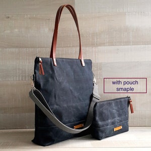 May include: A black canvas tote bag with brown leather handles and a gray adjustable shoulder strap. The bag has a zipper closure and a small matching canvas pouch with a zipper closure. The text "with pouch sample" is written in white on a black rectangle.
