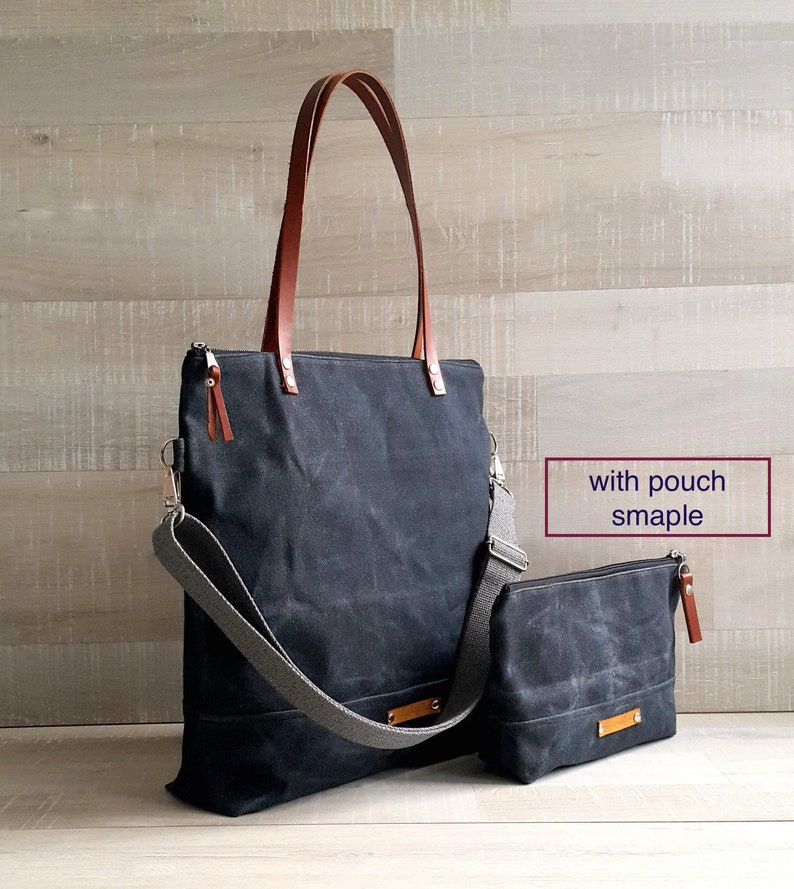 May include: A black canvas tote bag with brown leather handles and a gray adjustable shoulder strap. The bag has a zipper closure and a small matching canvas pouch with a zipper closure. The text "with pouch sample" is written in white on a black rectangle.
