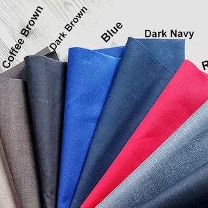 Op de afbeelding: Een selectie van gewaxte canvas stofstalen in verschillende kleuren, waaronder felgroen, legergroen, beige, koffiebruin, donkerbruin, blauw, donkerblauw, rood, grijs en antraciet.