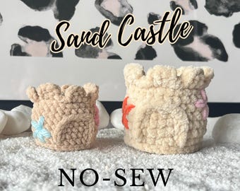 May include: Two crocheted sandcastle-shaped containers with colorful flower embellishments. The text "Sand Castle" and "NO-SEW" are visible in the image.