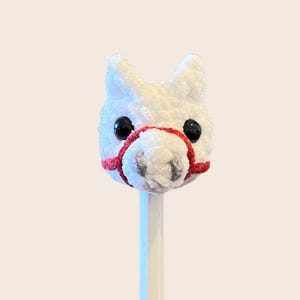 May include: White plush horse head with red bridle attached to a wooden pencil.