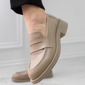 K&ouml;nnte beinhalten: Beigefarbene Lederschuhe mit einem dicken Absatz und einem schlichten Design.