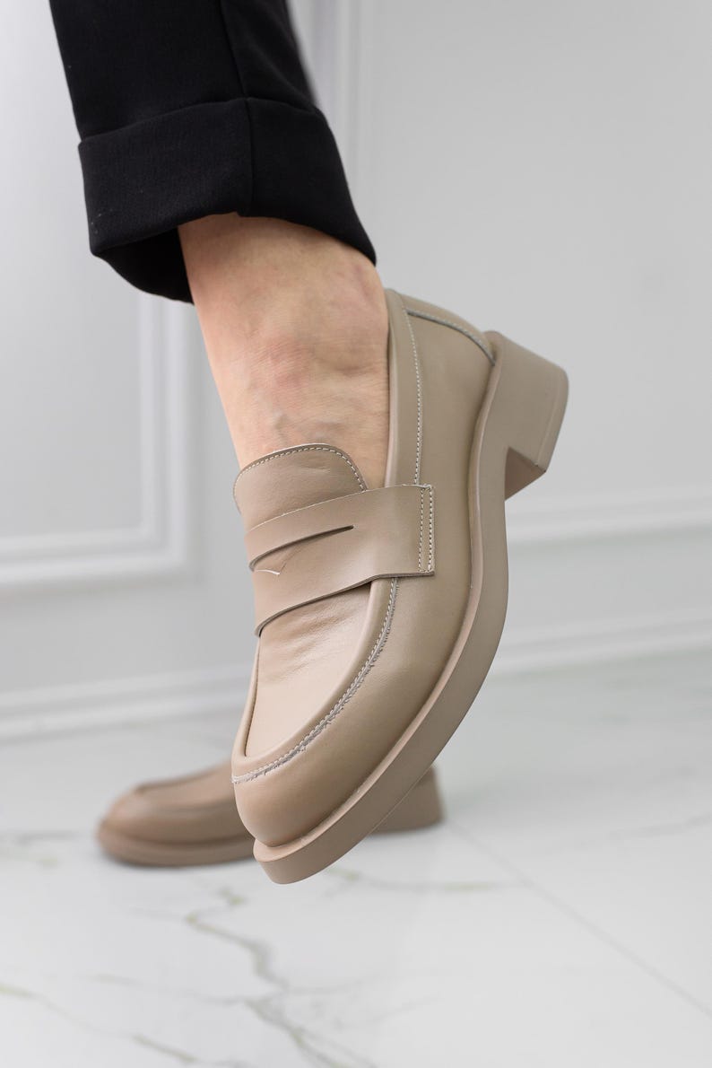 K&ouml;nnte beinhalten: Beigefarbene Lederschuhe mit einem dicken Absatz und einem schlichten Design.