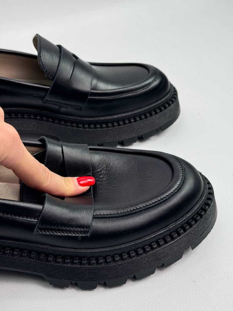 Puede incluir: Zapatos de vestir negros de cuero con suela de plataforma gruesa. Los zapatos de vestir tienen un dise&ntilde;o sencillo con una sola correa en la parte superior.