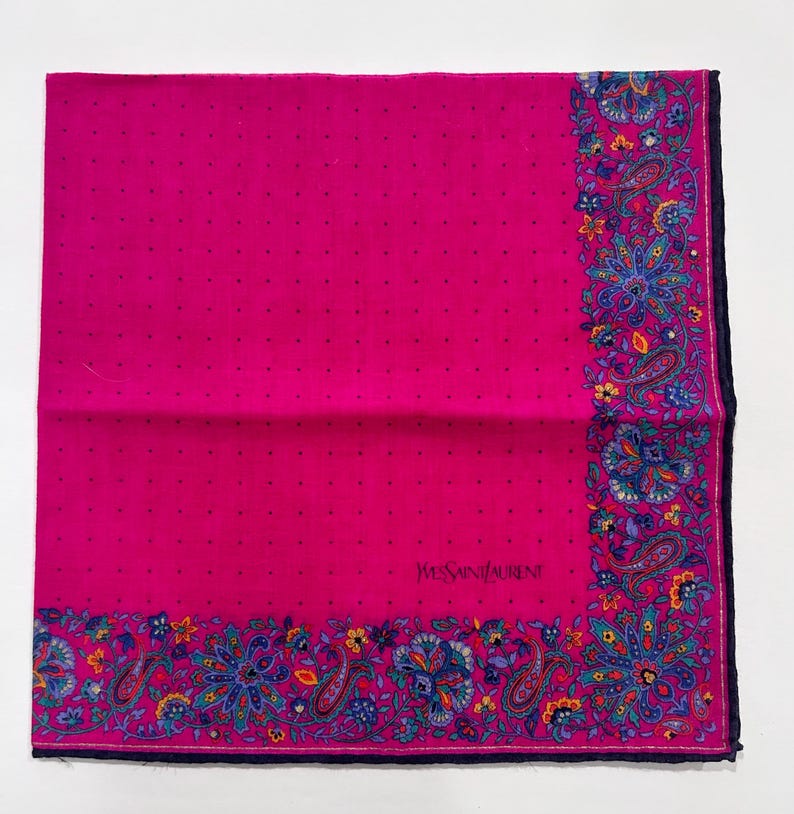 Puede incluir: Un pa&ntilde;uelo de seda rosa con un borde de paisley y el texto "Yves Saint Laurent" en negro.