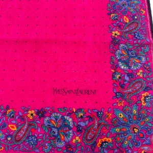 Puede incluir: Un pa&ntilde;uelo de seda rosa con un patr&oacute;n de lunares blancos y un borde paisley. El pa&ntilde;uelo tiene el texto "Yves Saint Laurent" bordado en negro.