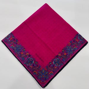 Puede incluir: Un pa&ntilde;uelo de seda rosa con un borde de paisley y el texto "Yves Saint Laurent" en el centro.