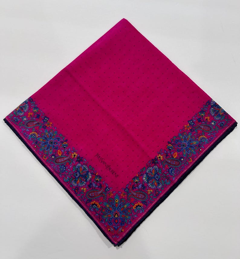 Puede incluir: Un pa&ntilde;uelo de seda rosa con un borde de paisley y el texto "Yves Saint Laurent" en el centro.
