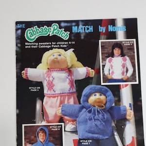 May include: A vintage magazine cover featuring Cabbage Patch Kids dolls and children wearing matching sweaters. The cover includes the text "THE Cabbage Patch MATCH by Nomis" and "Matching sweaters for children 4-14 and their Cabbage Patch Kids".