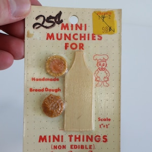 May include: A vintage card of miniature food items labelled "Mini Munchies For." The card includes two small, round pieces of "Handmade Bread Dough," a wooden cutting board, and a cartoon chef. The text reads "Mini Things (Non Edible)."