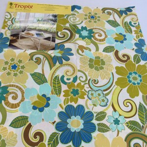 May include: A fabric sample with a large floral pattern in shades of blue, green, and yellow on a white background. The design includes stylized flowers, leaves, and swirling elements. A smaller image of a room setting is visible.