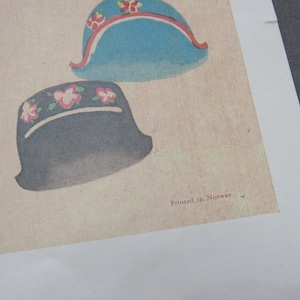 Puede incluir: Ilustraci&oacute;n de varios sombreros con elementos florales y decorativos. Los sombreros son en tonos de azul, negro y rosa, sobre un fondo crema. El texto "Printed in Norway" es visible.