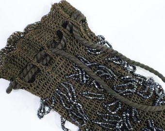 May include: A dark olive green crocheted handbag with a rope handle. The bag is embellished with strands of dark gray beads. The top edge has a scalloped design.