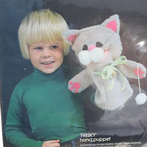 以下が含まれることがあります： Bucillaの「Frisky」ハンドパペットキット。ピンクのアクセント、緑のリボン、白いポンポンが付いた灰色の猫の人形が含まれています。キットはぬいぐるみ生地にスタンプされており、すべての材料と指示が含まれています。