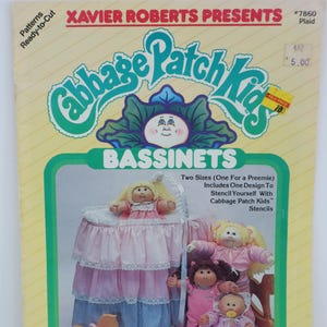 May include: A vintage Cabbage Patch Kids bassinet pattern book. The cover features the text "Xavier Roberts Presents Cabbage Patch Kids Bassinets." The book includes images of dolls and bassinets in pink and blue.