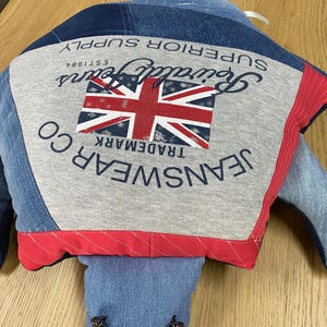May include: A blue denim turtle stuffed animal with a red, white, and blue Union Jack flag and the text "Superior Supply", "Grand Prix", "EST 1986", "TRADEMARK", "JEANSWEAR", and "CO" on the back.