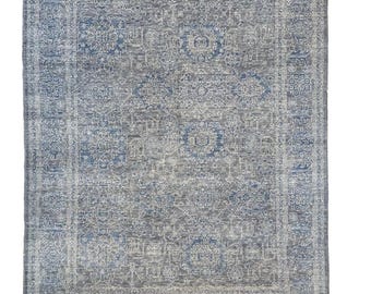 Puede incluir: Una alfombra azul y blanca con un diseño de medallón central. La alfombra tiene un aspecto desgastado y un brillo sutil.