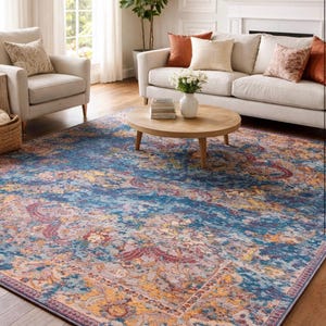 Può includere: Un grande tappeto rettangolare con un design vintage e usurato. Il tappeto presenta una miscela di tonalità blu, arancioni e rosse, creando un aspetto vibrante e invitante. Il tappeto è posto in un soggiorno.