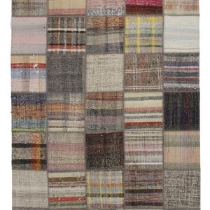Puede incluir: Una alfombra de patchwork con una variedad de colores y patrones, incluyendo rayas, cuadros y diseños florales. La alfombra está hecha de lana y tiene una textura tejida a mano.