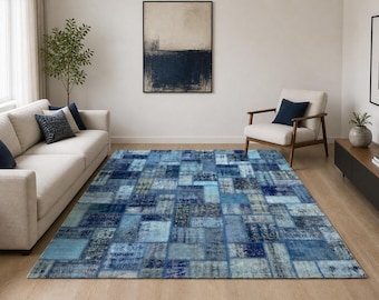 May include: A rectangular blue area rug with a patchwork design. The rug features various shades of blue, with lighter and darker squares creating a textured appearance. The rug is placed on a wooden floor in a living room setting.