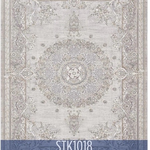 May include: A rectangular area rug with an ornate, symmetrical design in shades of gray and beige. The rug features a central medallion and detailed floral patterns. The text "STK1018" is displayed on a blue banner at the bottom.