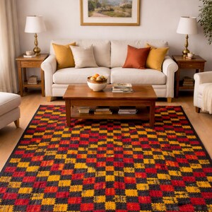 Può includere: Un soggiorno con un divano color crema con cuscini nei toni del giallo, beige e ruggine. Un tavolino e tavolini in legno affiancano il divano. Un grande tappeto con un motivo a scacchiera rosso, giallo e nero domina il pavimento.