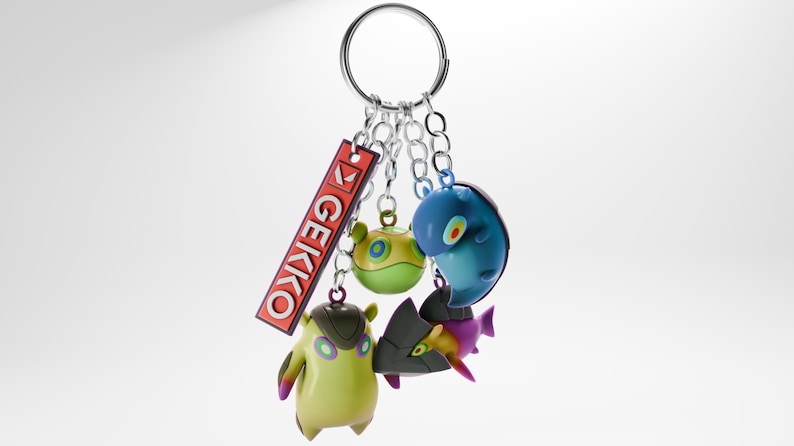 May include: A silver keychain with a red tag that says "GEIKKO" and four colorful plastic charms. The charms are a green and yellow creature, a blue creature, a purple and gray creature, and a purple and white creature.