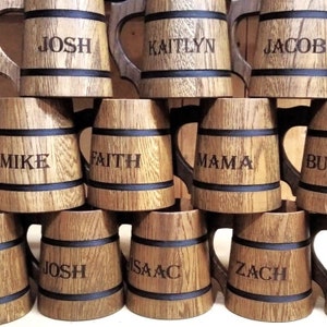 May include: A collection of wooden beer mugs with black bands and personalized names, including Josh, Kaitlyn, Jacob, Mike, Faith, Mama, and Zach.