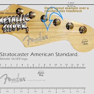 Può includere: Una paletta di chitarra Fender Stratocaster con un logo argento metallizzato. La paletta è in legno e ha una finitura naturale. Il logo è un adesivo argentato con le parole "Metallic Silver" in grassetto. La paletta presenta anche il logo Fender e le parole "Stratocaster" e "Made in USA".
