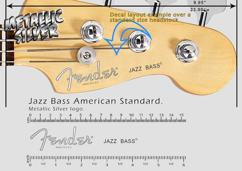 May include: A close-up of a Fender Jazz Bass guitar headstock with a metallic silver decal. The decal reads "Fender" and "JAZZ BASS" with "MADE IN U.S.A." underneath. The headstock is made of natural wood and has four tuning pegs. A ruler is shown below the headstock with measurements in inches and centimeters.