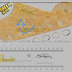 May include: A Fender Stratocaster guitar headstock decal with a metallic gold logo and the text "Fender Stratocaster with Synchronized Tremolo". The decal is designed for a standard size headstock and includes a signature from Jimi Hendrix.
