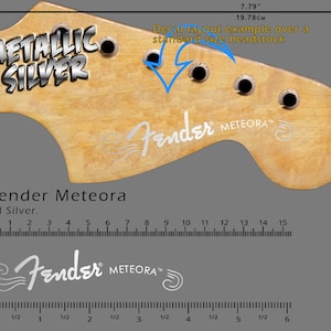May include: A light-colored guitar headstock with the text "METALLIC SILVER" and "Fender METEORA" in silver. The image includes measurements of 7.79 inches and 19.78 cm, along with a decal layout example.