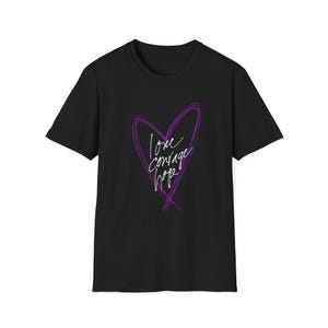 May include: Black t-shirt featuring a purple heart design with the words "love courage hope" in a handwritten style. The heart is outlined with a scribbled effect. The shirt has short sleeves and a crew neck.
