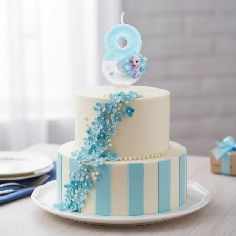 May include: A two-tier cake decorated with vertical light blue and white stripes, adorned with a cascading arrangement of small blue flowers and white pearls. A light blue number eight candle featuring a character graphic sits on top.
