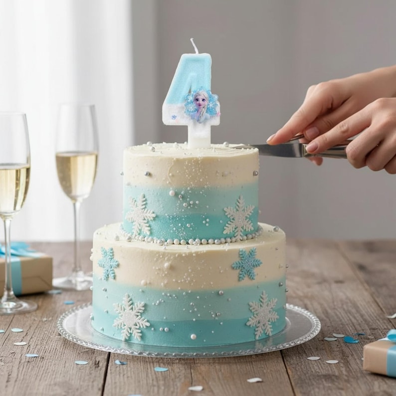 May include: A two-tiered cake with light blue and white frosting, decorated with white snowflake cutouts and silver sprinkles. A light blue number four candle featuring a small image of a character is placed on top of the cake.