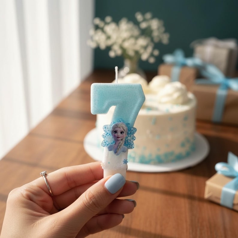 May include: A light blue number seven birthday candle with a glittery finish, featuring a small, detailed illustration of a character with blonde hair and a blue dress attached to the front, topped with a single white wick for lighting.