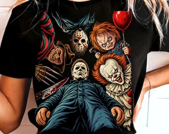 May include: A black t-shirt featuring a graphic print of various horror movie characters, including a masked figure in a blue jumpsuit, a clown with a red balloon, a doll with orange hair, a hockey mask, and a figure with a bladed glove.