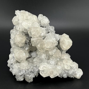 May include: A cluster of white calcite crystals with a rough, textured surface. The crystals are arranged in a random, organic pattern, creating a unique and interesting display.