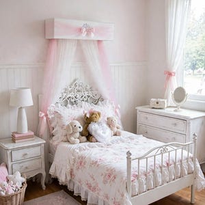 May include: A white metal bed frame with a floral patterned duvet and ruffled edges, featuring a wall-mounted canopy with pink and white tulle fabric. The bed is adorned with three plush stuffed animals and a heart-shaped pillow in the center.