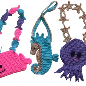 Può includere: Tre borse a mano all'uncinetto a forma di creature marine con tracolle. La prima è una balena rosa con una tracolla di pesce blu e viola. La seconda è un cavalluccio marino marrone e blu con una tracolla marrone. La terza è un polpo viola con una tracolla di stella marina marrone.